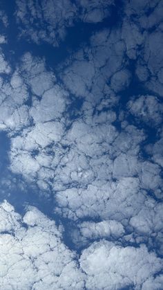 an airplane is flying high in the sky above some clouds and blue sky with white fluffy clouds