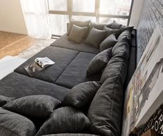 a couch that is sitting in the middle of a living room with pillows on it