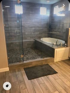 a bathroom with wood flooring and gray tile on the walls, along with a walk in shower