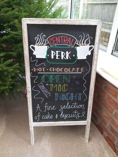 a chalkboard sign with writing on it in front of a window next to a christmas tree