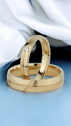 two gold wedding rings sitting on top of each other