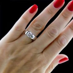 a woman's hand with red nails and a ring on it