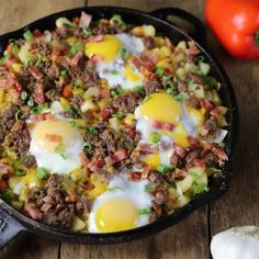 an iron skillet filled with eggs, meat and vegetables