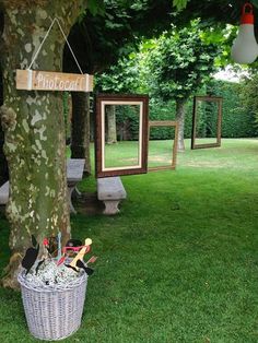 a basket full of items sitting under a tree in the grass next to two mirrors