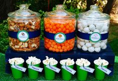 a table topped with lots of different types of candies and popcorns on top of green cups