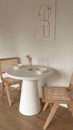 a white table and chairs in a room with wood flooring next to a plant