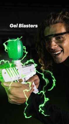 a young man holding a green light up nerf blaster in his right hand