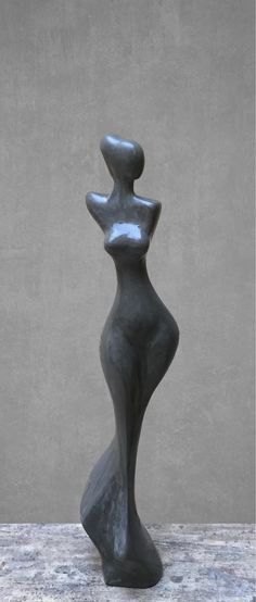 a black sculpture sitting on top of a wooden table next to a gray wall and floor