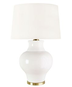 a white table lamp with a gold base and a white linen shade on the top