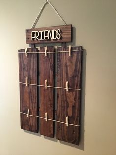 a wooden sign hanging from the side of a wall with clothes pins attached to it