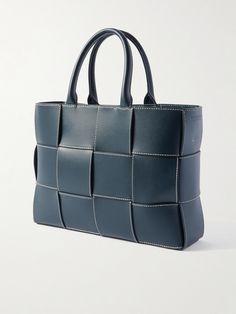 Bottega Veneta specialises in quiet luxury and understated elegance. In a scaled-down version of the label's signature intrecciato weave, this 'Mini Arco' tote bag has been crafted in Italy from navy leather with contrast stitching and left unlined to show off the expert workmanship. The brand recommends filling it with tissue paper to maintain its shape and absorb humidity when stored away. Porter Bag, Latest Bags, Quiet Luxury, Navy Leather, Leather Messenger Bag, The Expert, Understated Elegance, Leather Messenger, Leather Pouch