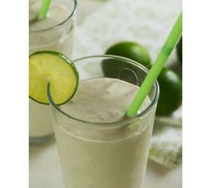 two glasses filled with smoothie next to limes