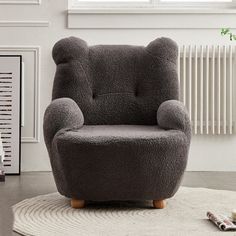 a gray chair sitting on top of a rug in a living room next to a radiator