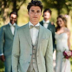 a man in a suit and bow tie standing next to other men