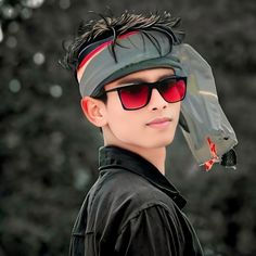 a young boy wearing sunglasses and a hat with feathers on it's head is looking at the camera