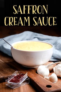 a bowl of saffron cream sauce on a cutting board next to garlic and cloves