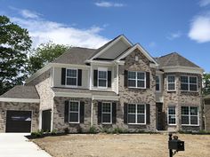 a large brick house with two garages on the front and one car parked in front