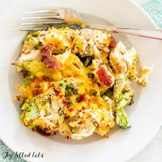 a white plate topped with broccoli and chicken casserole next to a fork