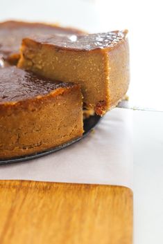 a cake sitting on top of a wooden cutting board next to a piece of pie