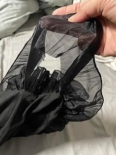 a hand holding a black plastic bag on top of a bed