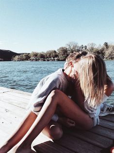 two people are sitting on a dock by the water and one person is holding his head