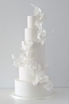 a three tiered white wedding cake with flowers on top