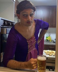 a woman in a purple dress holding a glass of beer and looking at the camera