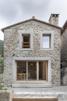 a stone house with two windows and steps leading up to it