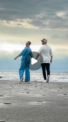 two people are walking on the beach together