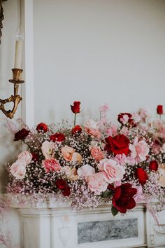 a bunch of flowers sitting on top of a fireplace