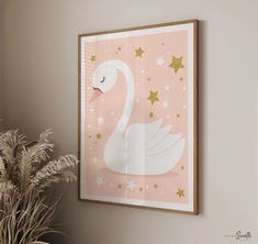 a pink and gold swan print hangs on the wall next to a potted plant