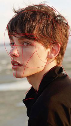 a young man with red lines on his face and hair in front of the ocean