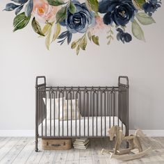 a baby crib in front of a floral wall mural