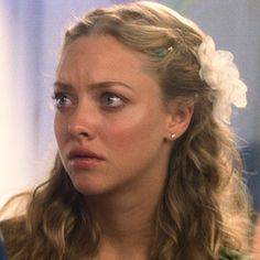 a close up of a person wearing a flower in her hair and looking off to the side