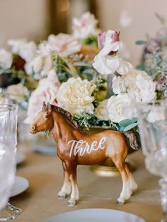 there is a horse figurine on the table with flowers in the vases