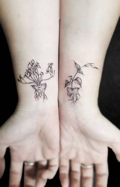 two small tattoos on both hands with flowers and leaves tattooed on the wrist, in front of each other