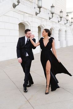 a man and woman in formal wear walking down the street together, both dressed in black