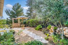 an outdoor garden with trees and plants in the background, including a stone path that leads to a picnic table