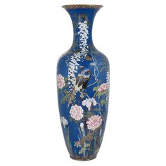 a blue vase with birds and flowers painted on the side, sitting against a white background