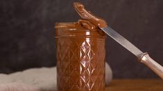 a jar filled with peanut butter next to a knife