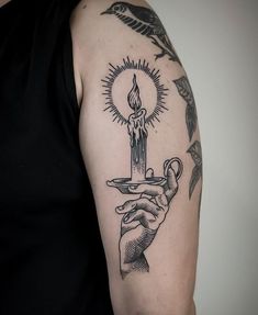 a person with a tattoo on their arm holding a candle