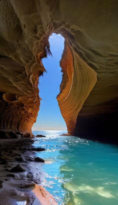 the inside of a cave with blue water and rocks on either side, looking out to sea