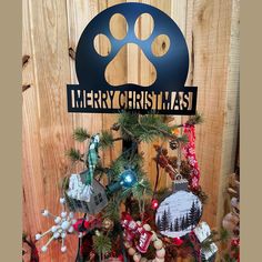 a christmas tree with ornaments and a dog's paw on the sign that says merry christmas