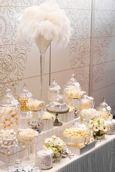 a table topped with lots of desserts next to a tall vase filled with flowers