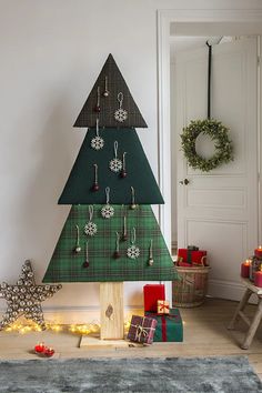 a christmas tree made out of wood with ornaments hanging from it's sides and presents under the tree