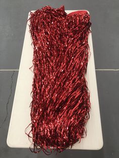 a piece of red tinsel sitting on top of a white cutting board