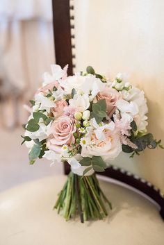 a bouquet of flowers sitting on top of a white table next to a wooden chair