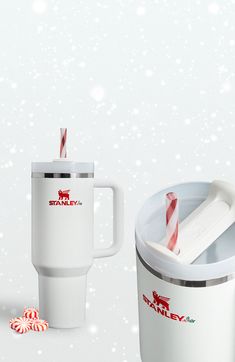 a white coffee cup with a straw in it next to a red and white candy cane