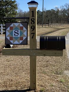 a mailbox sitting on top of a wooden post next to a sign with the letter s