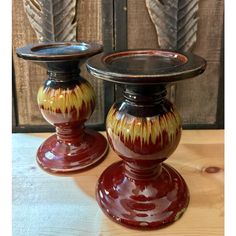 two red and yellow vases sitting on top of a wooden table next to each other